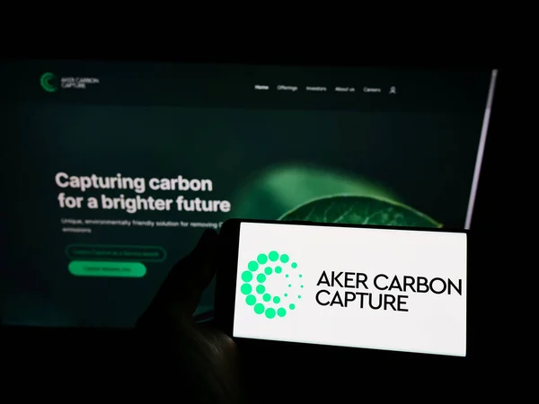 手握智能手机在电脑屏幕前 其符号为Aker Carbon Capture — 图库照片