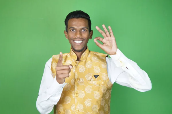 身穿绿色衬衫和黄色毛衣的非洲裔美国人在彩色背景上做出了不错的手势 — 图库照片