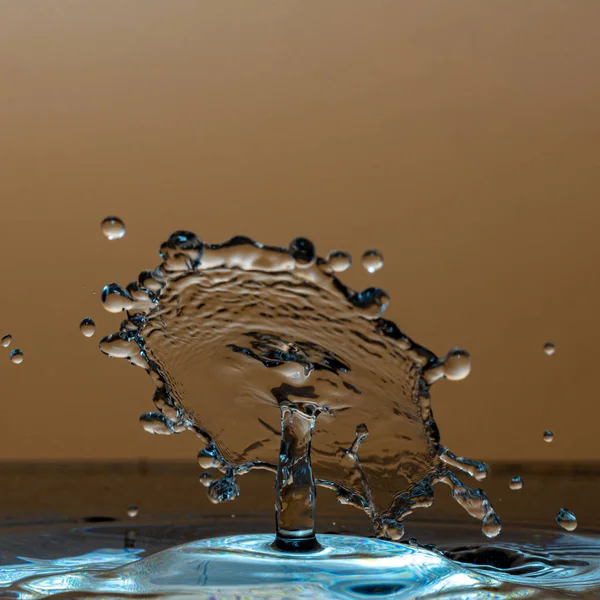 Water Spatten Een Beige Achtergrond — Stockfoto