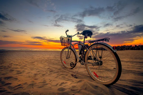 日落时骑自行车在海滩上 — 图库照片
