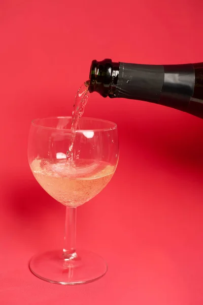 Nalewanie Czerwonego Wina Szklanki Różowym Tle — Zdjęcie stockowe