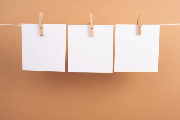 stock image blank paper note on a rope on a yellow background