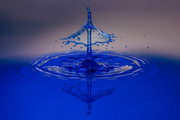 Капля Воды Падает Голубом Фоне — стоковое фото