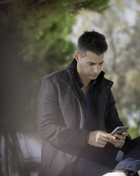Genç Adam Parkta Oturuyor Cep Telefonu Kullanıyor — Stok fotoğraf