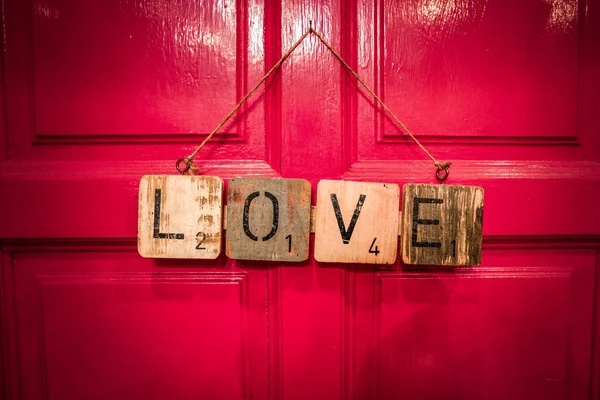 Słowo Miłość Napisana Drewnianych Listach Czerwonym Tle — Zdjęcie stockowe