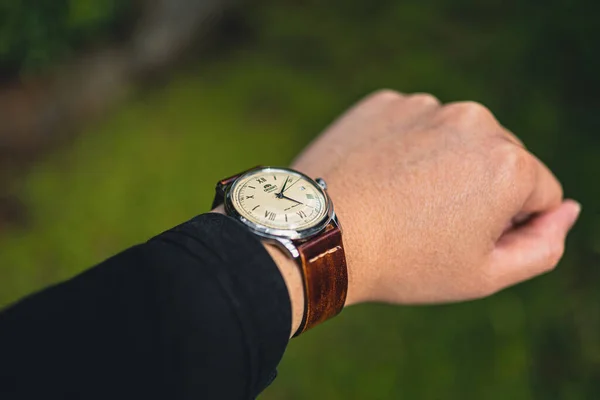 緑の背景に時計を持っている男の手 — ストック写真