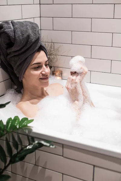 シャボン玉の入った風呂にいる若い女性 — ストック写真