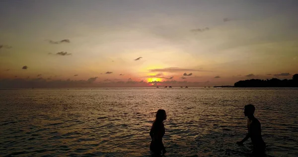 日没時にビーチでカップルのシルエットが — ストック写真