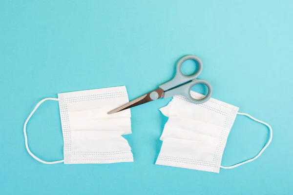 medical mask and scissors on a blue background