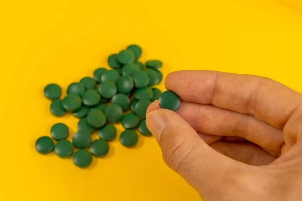 Mano Sosteniendo Píldoras Verdes Sobre Fondo Amarillo —  Fotos de Stock