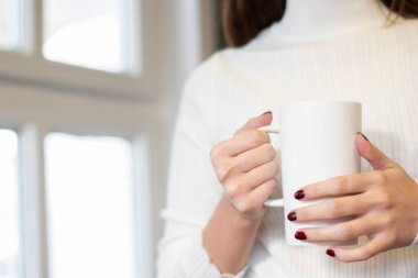 Ofis arka planında kahve fincanı tutan kadın eli.