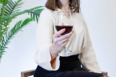 Beyaz elbiseli kadın şarap kadehinden şarap içiyor.