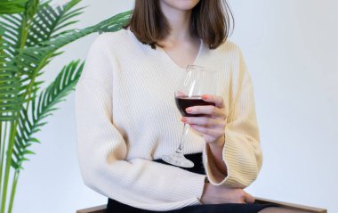 Beyaz elbiseli kadın şarap kadehinden şarap içiyor.