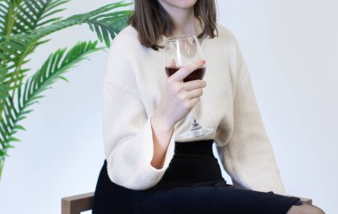 Beyaz elbiseli kadın şarap kadehinden şarap içiyor.