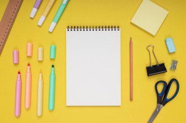 notepad, scissors, pencil, sharpener, ruler, eraser, colored pencils, clips and note paper. back to school. Isolated yellow background
