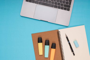 Laptop, notepad, pencil, eraser, colored pencils. back to school. Isolated blue background