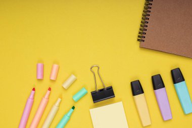 Notebook, colored pencils, note paper and clamp. back to school. Isolated yellow background