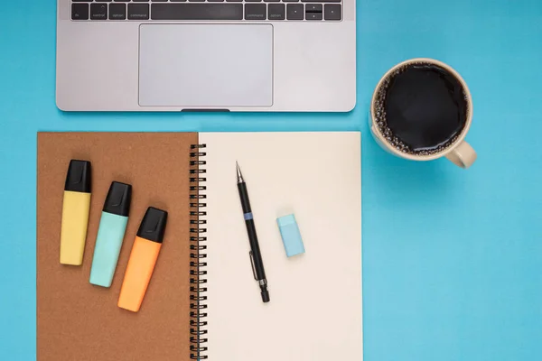 Laptop, notepad, pencil, eraser, colored pencils, coffee mug. back to school. Isolated blue background