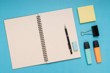 notepad, pencil, eraser, colored pencils, clips and note paper. back to school. Isolated blue background