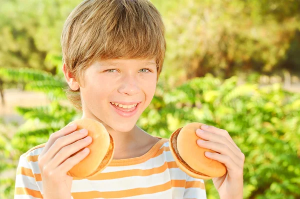 Smiling child holding two burgers — Stock Photo, Image