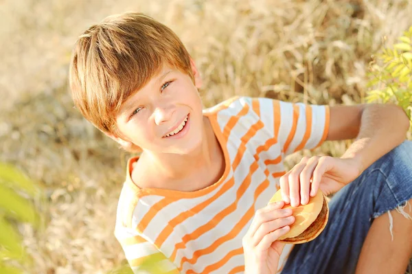 Happy child eating hamburger — Stock Photo, Image