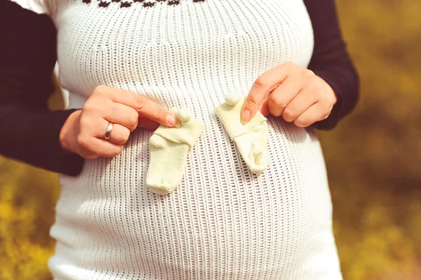 Donna incinta con piccoli calzini sulla pancia — Foto Stock