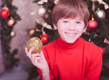 şirin odada Noel topu tutan çocuk boy gülümseyerek