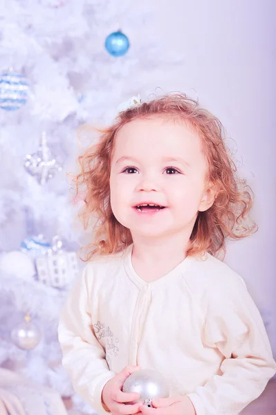 Niedliches lächelndes Baby Mädchen hält Weihnachtskugel drinnen — Stockfoto