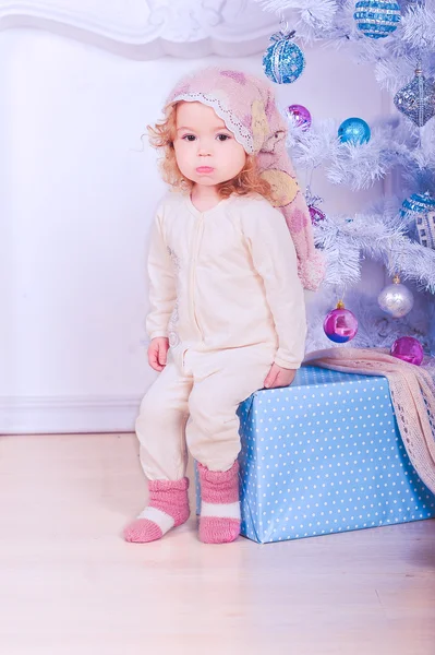 Schattige babymeisje zit onder kerstboom — Stockfoto