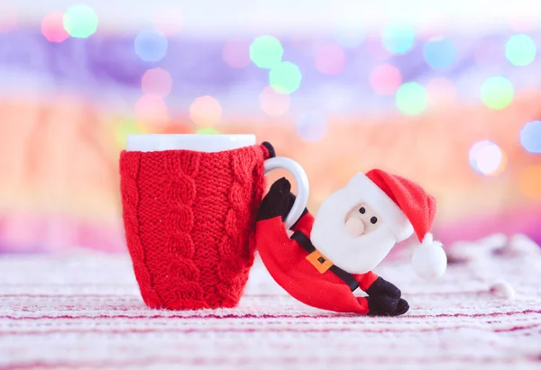 Knitted cup with santa claus at christmas lights — Stock Photo, Image