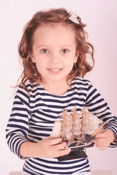 Menina bonito segurando brinquedo navio no estúdio — Fotografia de Stock