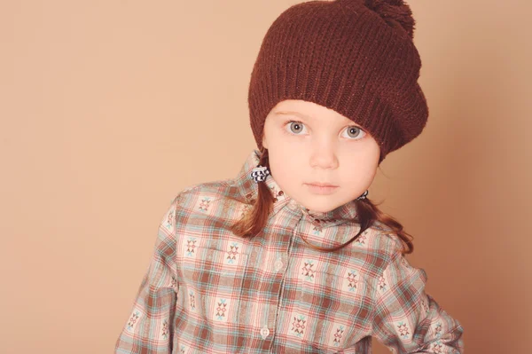 Söt liten flicka klädd i stickad mössa i studio — Stockfoto