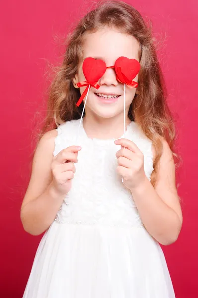 Smiling little girl playing with valentine's hearts — Stock Photo, Image