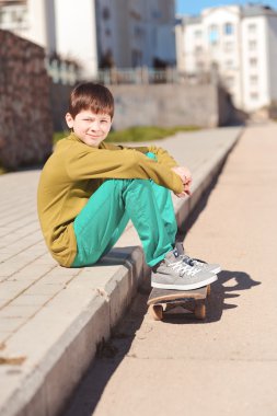 Kaykayda oturan çocuk.