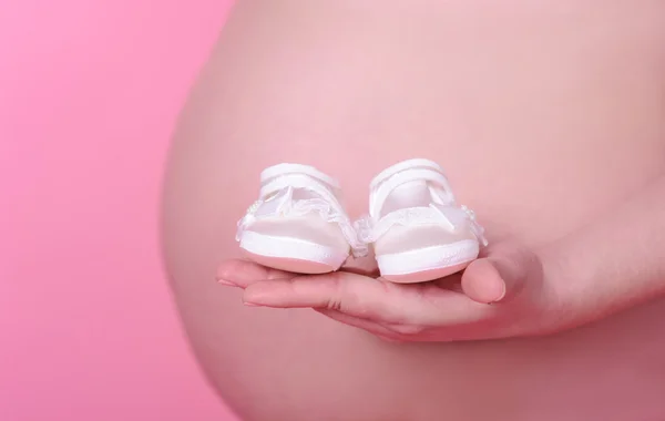 Bebek ayakkabısı tutan hamile kadın. — Stok fotoğraf