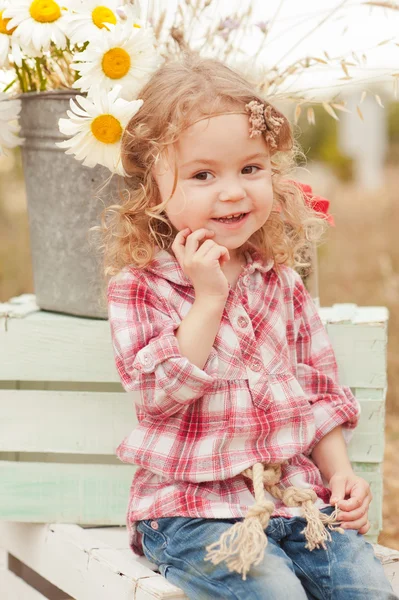 Girl sitting on boxes in meadow — Stock Photo, Image