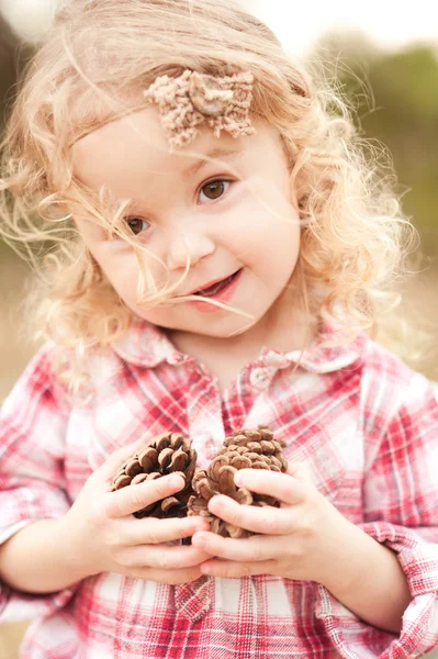 Meisje houden dennenappels — Stockfoto