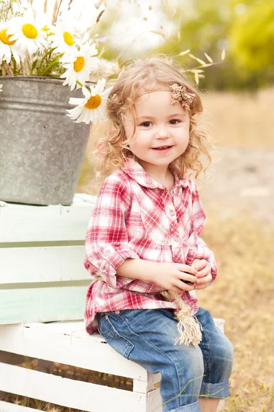 Girl sitting on crates with decorations — Stock Photo, Image