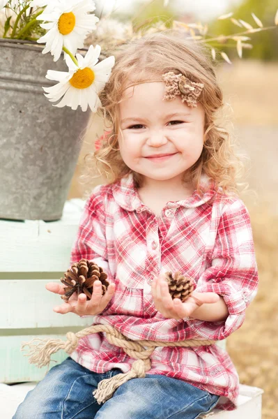 Meisje houden dennenappels — Stockfoto