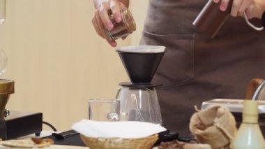 A professional barista pours water over the coffee grounds in the filter as a manual process. CU Shot, 4k Slow Motion video (The submitted footage is a grouping shooting arrangement)