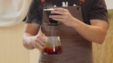 A professional barista pours water over the coffee grounds in the filter as a manual process. CU Shot, 4k Slow Motion video (The submitted footage is a grouping shooting arrangement)