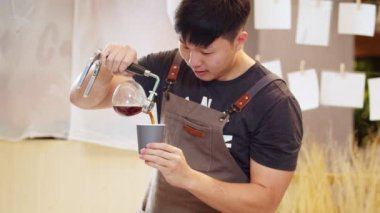 A professional barista pours the brewed coffee into a cup. Slow Motion 4K DCI (The submitted footage is a grouping shooting arrangement)