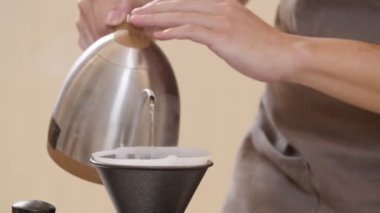 A professional barista pours water over the coffee grounds in the filter as a manual process. CU Shot, 4k Slow Motion video (The submitted footage is a grouping shooting arrangement)