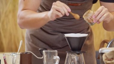 A professional barista pours water over the coffee grounds in the filter as a manual process. CU Shot, 4k Slow Motion video (The submitted footage is a grouping shooting arrangement)