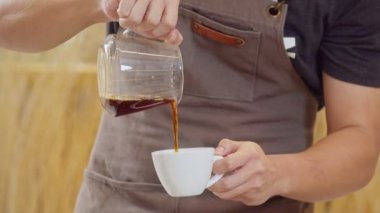A professional barista pours the brewed coffee into a cup. Slow Motion 4K DCI (The submitted footage is a grouping shooting arrangement)