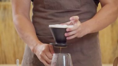 A professional barista pours water over the coffee grounds in the filter as a manual process. CU Shot, 4k Slow Motion video (The submitted footage is a grouping shooting arrangement)