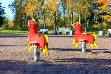 Bankların arkasında kırmızı renkte salıncaklar var.