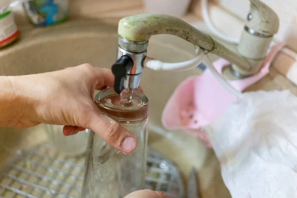 女人在水槽里把杯子里的水冲洗干净 — 图库照片