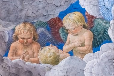 Antik duvardaki renkli freskin ayrıntıları bulutların arasında bir grup melek sarışın oğlanı gösteriyor.