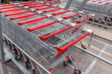 Süpermarket arabaları depoda birbiri ardına, kırmızı saplı çelik yük arabaları. 